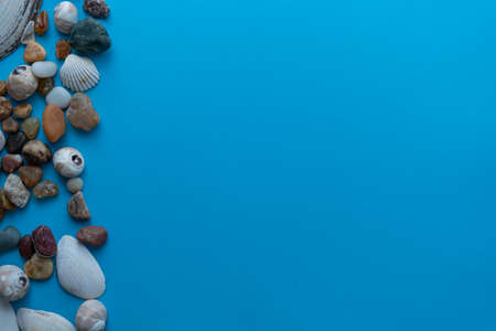 Flat lay composition sea pebbles and seashells on a blue background. space for textの写真素材
