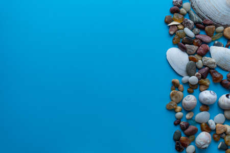 Flat lay composition sea pebbles and seashells on a blue background. space for textの写真素材