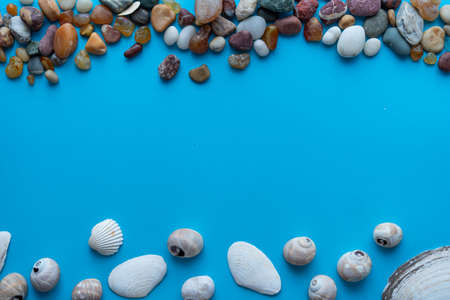 Flat lay composition sea pebbles and seashells on a blue background. space for textの写真素材