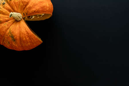 Flat composition orange pumpkin with a cut slice on a black background. A place for text.の写真素材