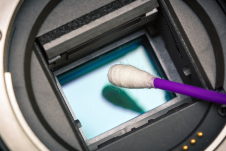 APS-C image sensor inside camera being cleaned with a cue tip.の写真素材
