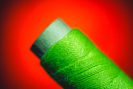 Green sewing thread closeup on red backgroundの写真素材