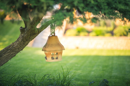 Clay or ceramic bird feeder hanging on a tree in the garden, soft blurry backgroundの写真素材