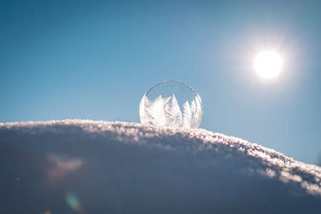 Frozen soap bubble with a beautiful pattern on the snow close up on a blurry backgroundの写真素材