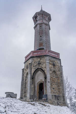 Lookout tower Stepanka on the border of Krkonose and Jizera Mountains. Winter overcast day, sky with clouds, trees covered with snow.の写真素材