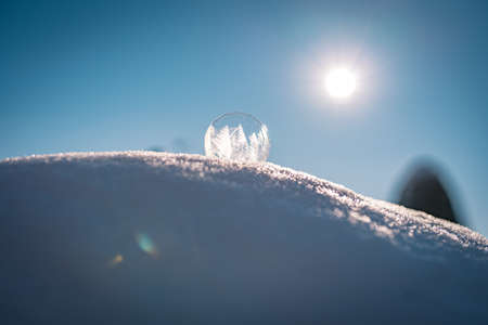 Frozen soap bubble with a beautiful pattern on the snow close up on a blurry backgroundの写真素材