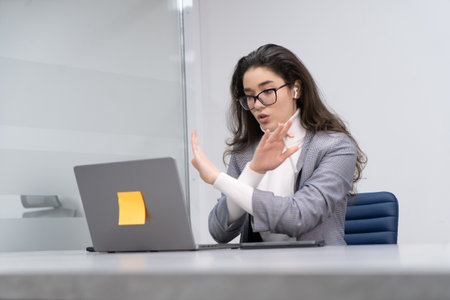 Young business woman expressing her disagreement at an online meeting, working from a modern officeの写真素材