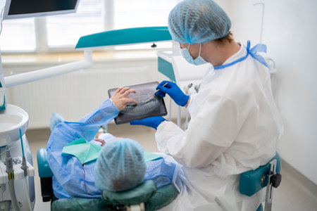 Dentist showing dental x ray to patient in cabinetの写真素材
