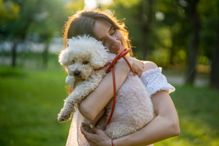 Affectionate young woman spending leisure time with cute dog in parkの写真素材
