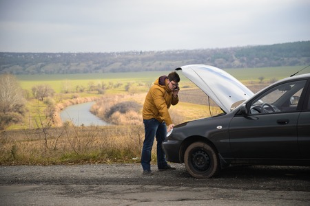 man with broken car in the middle of the road