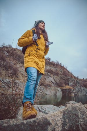 Woman in boots and jeans walks along the lake shore in autumn careerの写真素材