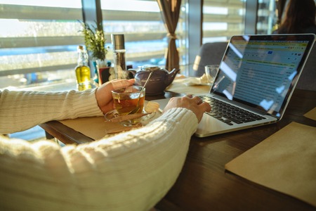 male sitiing in caffe drinking tea and working on laptopの写真素材