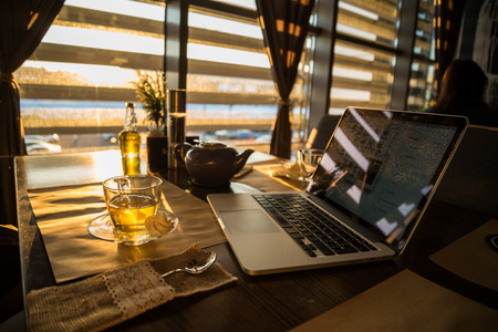 man in sweater working on laptop in caffe on sunsetの写真素材