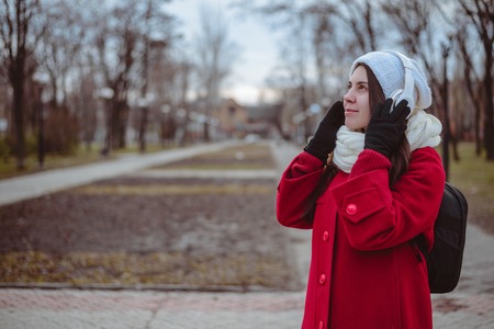 Portrait of a happy girl listening music on line with wireless headphones from a smartphone in hat