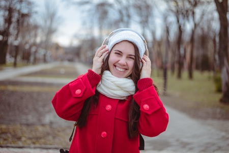 Portrait of a happy girl listening music on line with wireless headphones from a smartphone in hatの写真素材