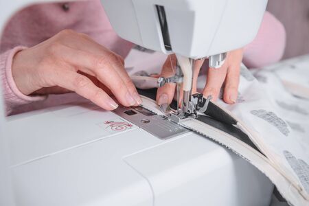 beautiful woman seamstress sew on the sewing machine clothes. sewing workshopの写真素材
