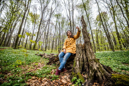 Young beautiful girl sitting and make selfie in forest