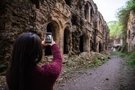 Young woman tourist photographing old ruinsの写真素材