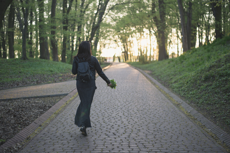 woman walking by park with flowers in handsの写真素材