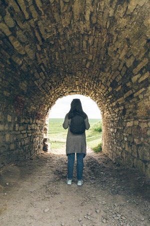 woman stands in tunnel of old castleの写真素材