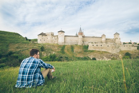 man sits alone in front of old castleの写真素材