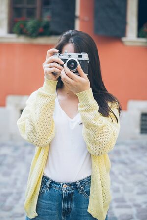 young pretty woman taking picture with old cameraの写真素材