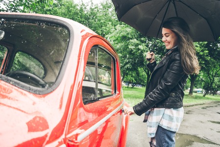 woman with umbrella sits in red retro carの写真素材