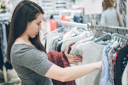 young woman choosing clothes in storeの写真素材