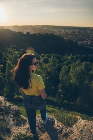 young woman with long dark hair on the peak of the hillの写真素材
