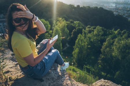 woman smilling on the top of the hill with mobileの写真素材