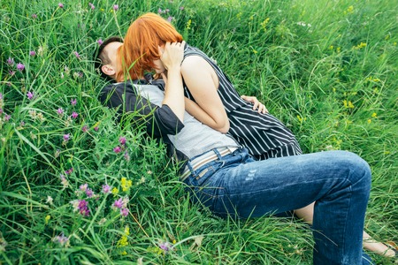 Young happy beautiful couple man and woman lying outdoors on the bright sunny day on green lawnの写真素材