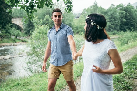 young pretty couple walking near mountains riverの写真素材