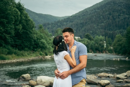 couple stands near mountain river with mountains on backgroundの写真素材