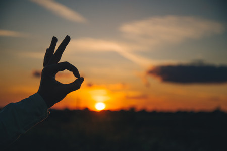 hands show ok sign on sunsetの写真素材