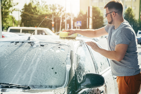 man woshing his car with spongeの写真素材