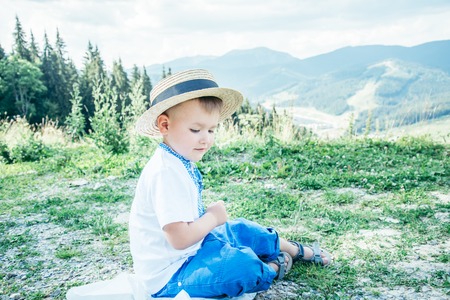 little boy sitting on the ground on the top of the mountainsの写真素材