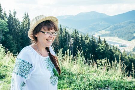 mature woman stands on the top of the hill and enjoys the viewの写真素材