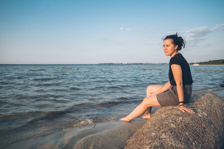 woman sits on the rock and lookin for lake viewの写真素材
