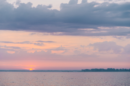 Beautiful blazing sunset landscape at black sea and orange sky above it with awesome sun golden reflection on calm waves as a background. Amazing summer sunset view on the beach.の写真素材