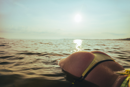 woman butt in the water in thong panties on sunrise in the waterの写真素材
