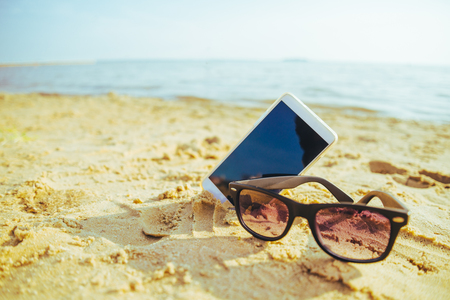phone on the beach with sunglassesの写真素材