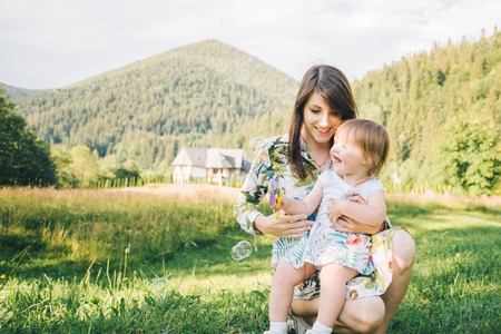 mother holds little daughter on her knees outsideの写真素材