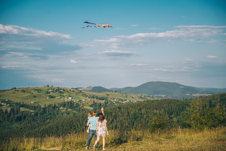 family running through field letting kite flyの写真素材