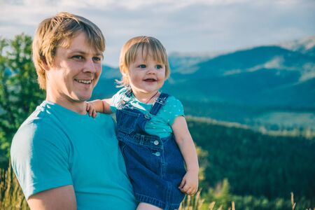 father and little daughter on his hands on the top of the mountainsの写真素材