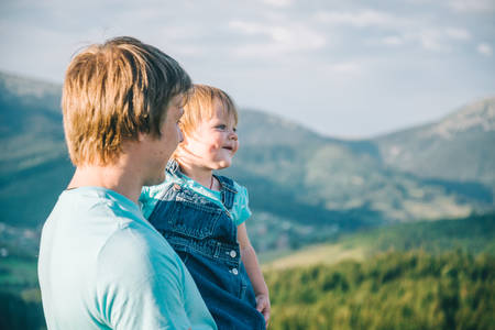 father and little daughter on his hands on the top of the mountains