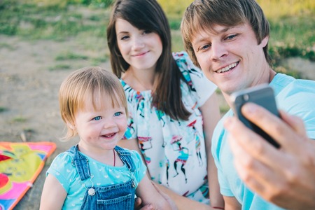 happy young family taking selfie while playing with kiteの写真素材