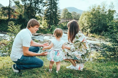 happy family play with daughter near the river in mountainsの写真素材