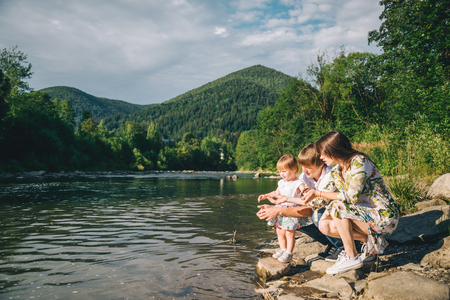 young family sits near mountain river with their daughterの写真素材