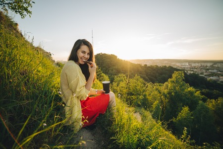 young pretty woman sitting on the peak of the hillの写真素材