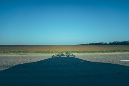 road with shadow of the car with bicycle on the roofの写真素材